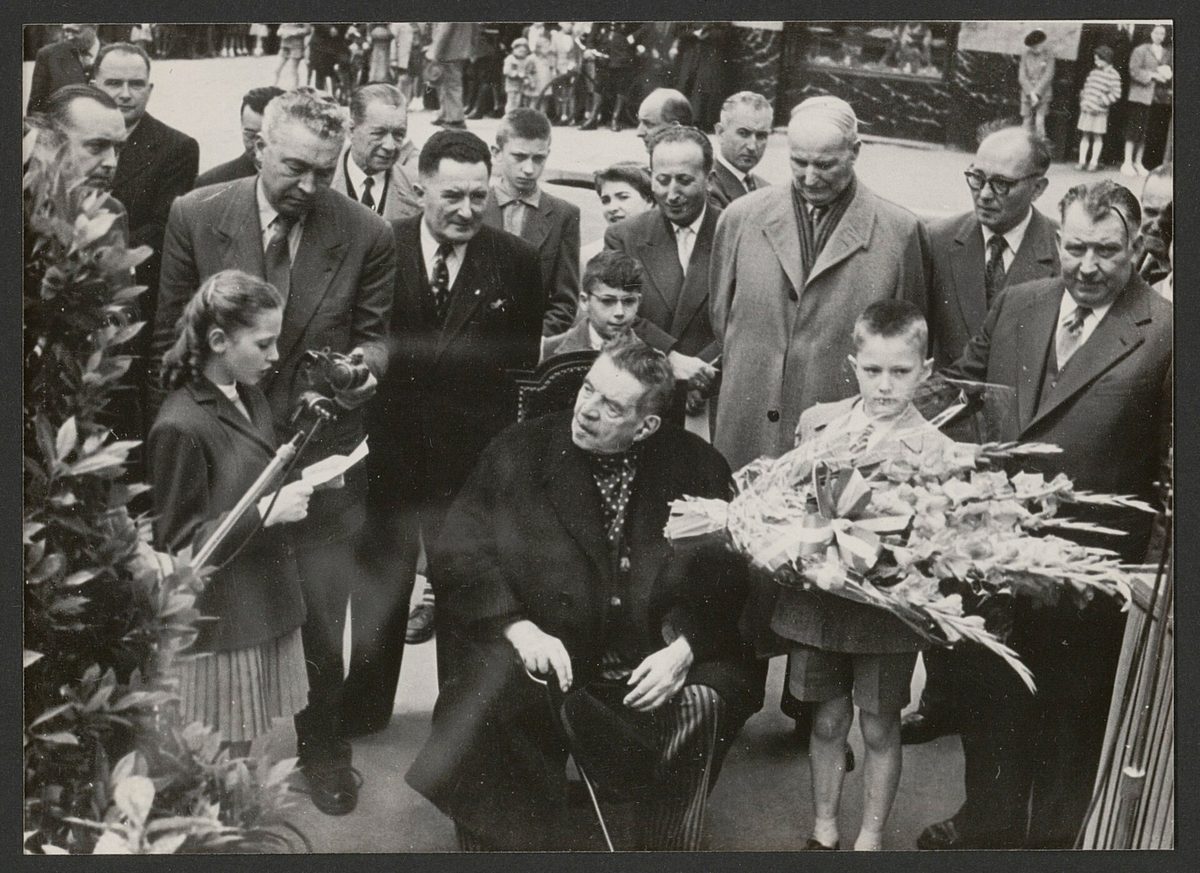 Édouard Herriot âgé, assis, entouré d’officiels et d’enfants portant des fleurs