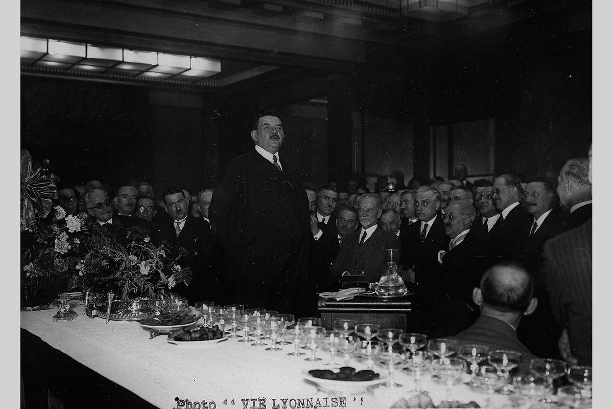 Édouard Herriot debout, prononçant un discours devant une longue table de banquet