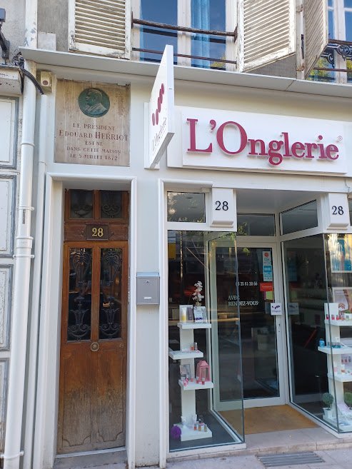 Façade d’immeuble au numéro 28, avec une porte en bois surmontée d’une plaque commémorative ornée d’un médaillon à l’effigie d’Édouard Herriot